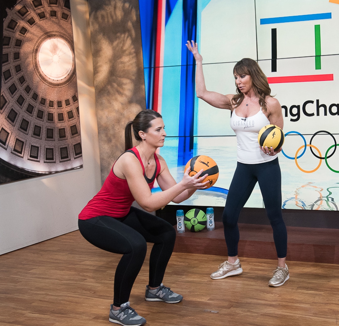 Woman doing squat with Smart Medicine Ball while trainer instructs