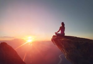 woman sits on boulder in mindful seated position