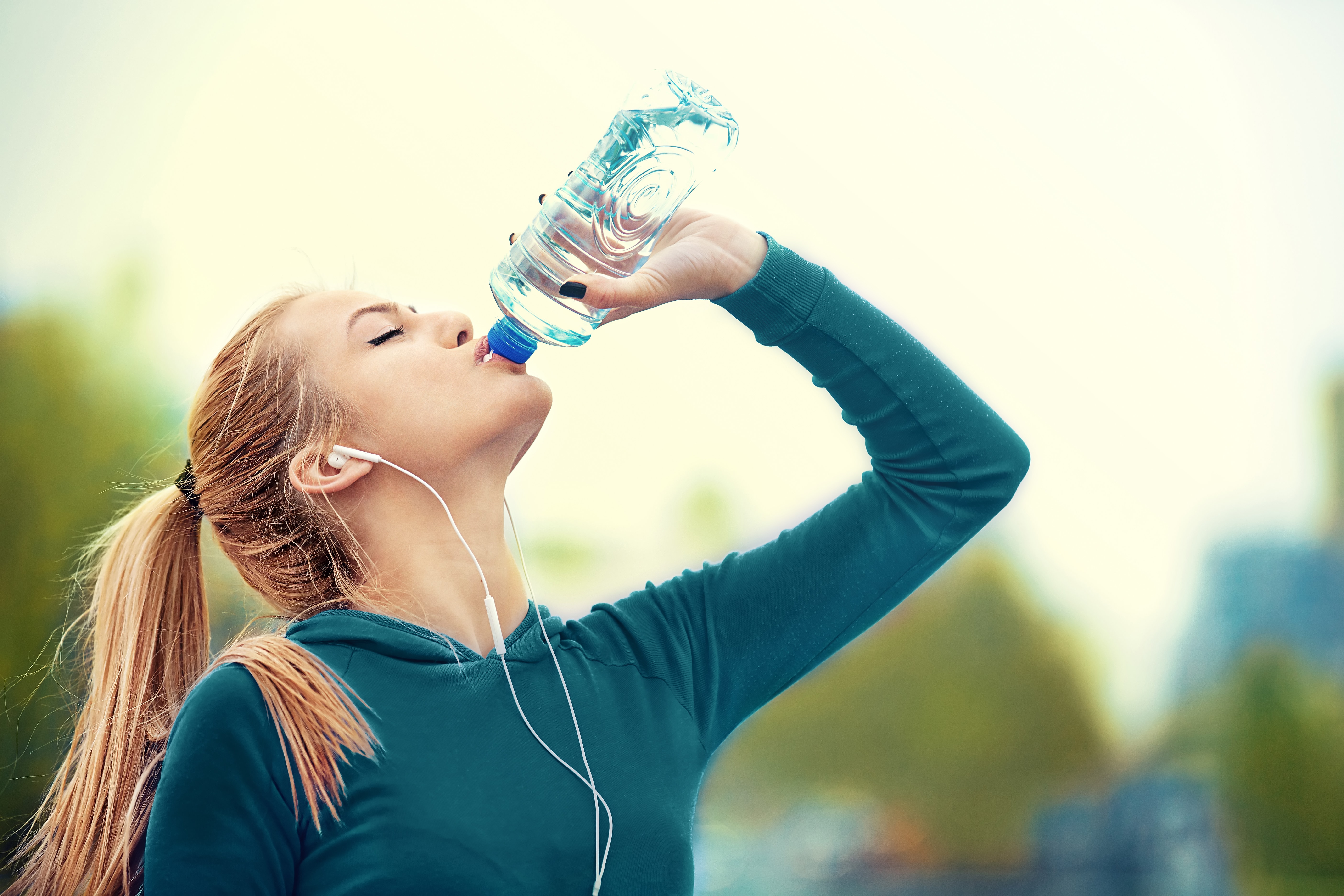 young woman drinking from clear water bottle
