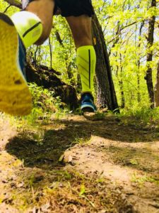 Man running on a forest trail with yellow shoes and stockings